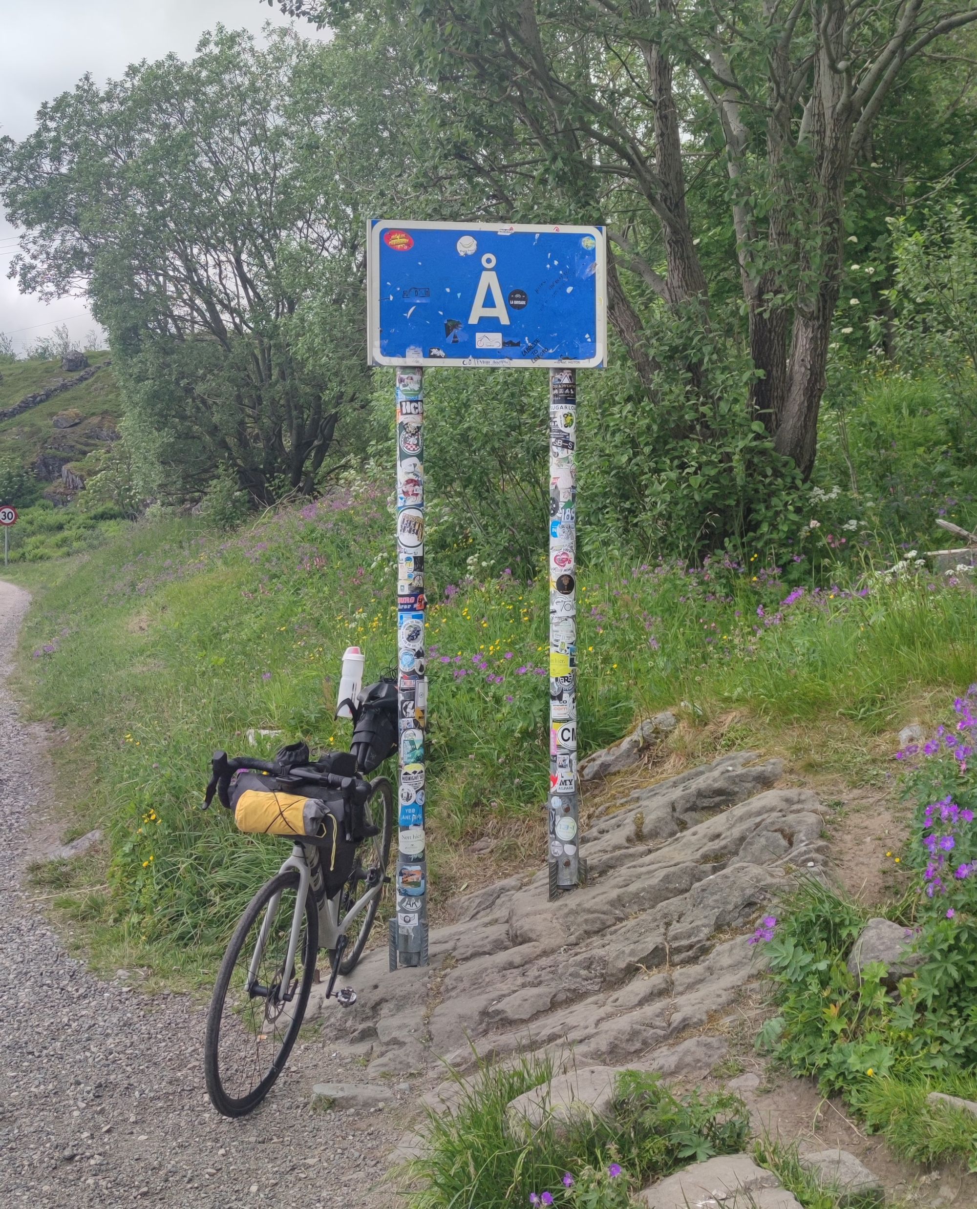 My bike next to the sign of the last village